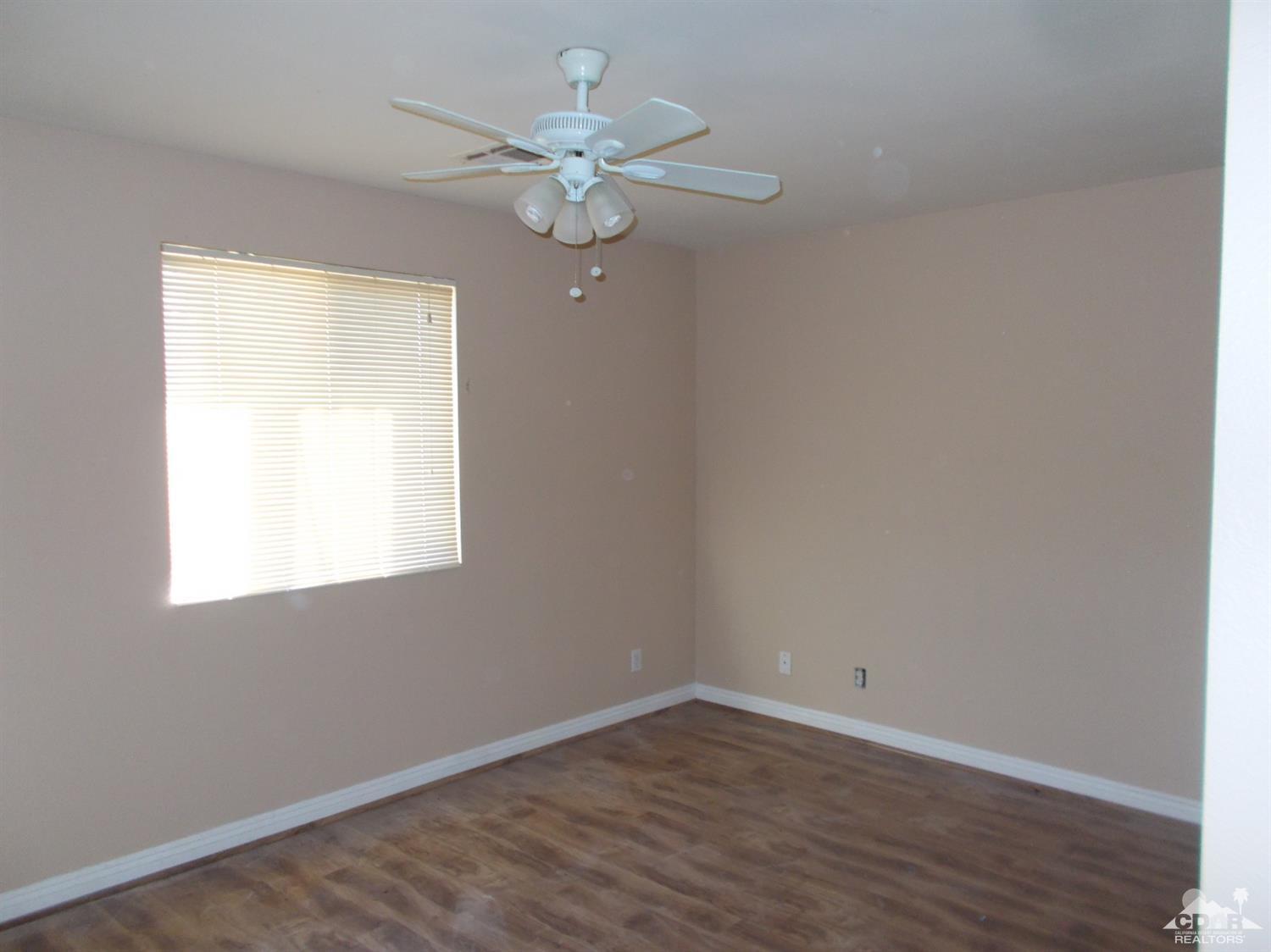 13080 Mountain View Road Desert Hot Springs, CA 92240 - Photo 4 of 11 an empty room with wooden floor and windows