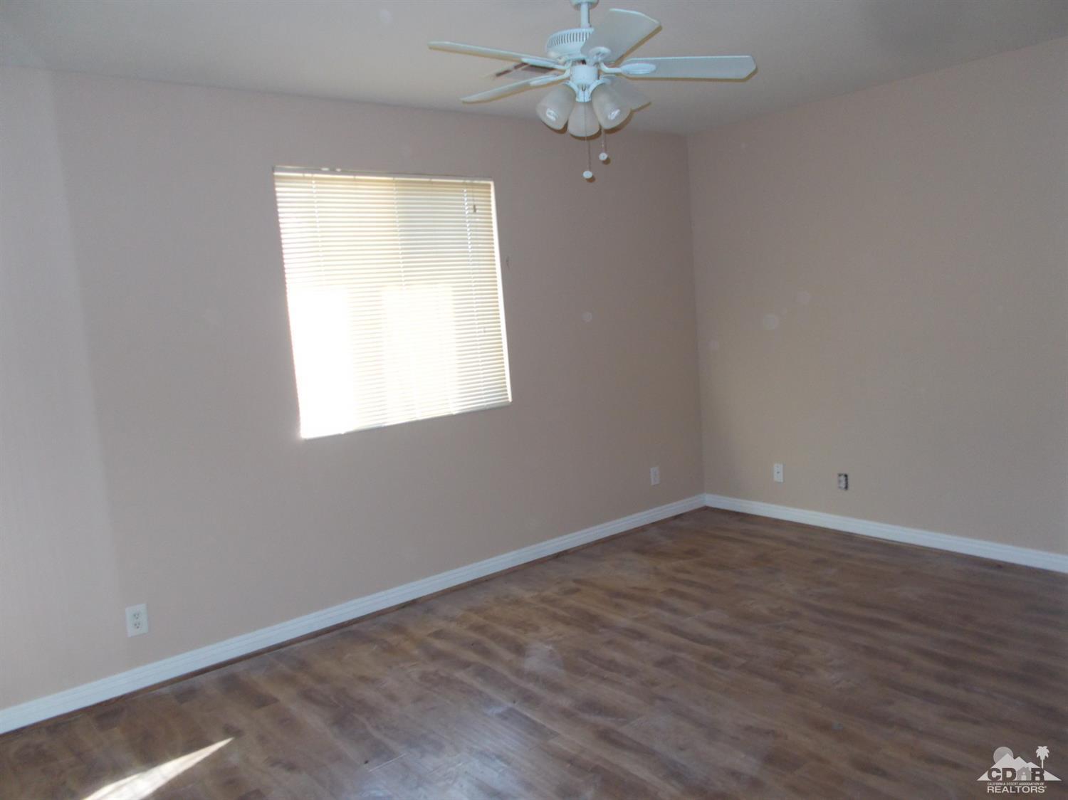 13080 Mountain View Road Desert Hot Springs, CA 92240 - Photo 5 of 11 an empty room with wooden floor and windows