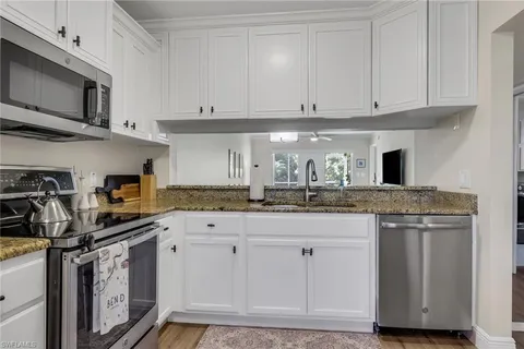 a kitchen with stainless steel appliances granite countertop a stove a sink and a white cabinets