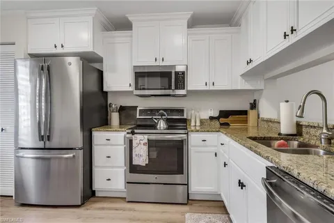 a kitchen with white cabinets stainless steel appliances and sink