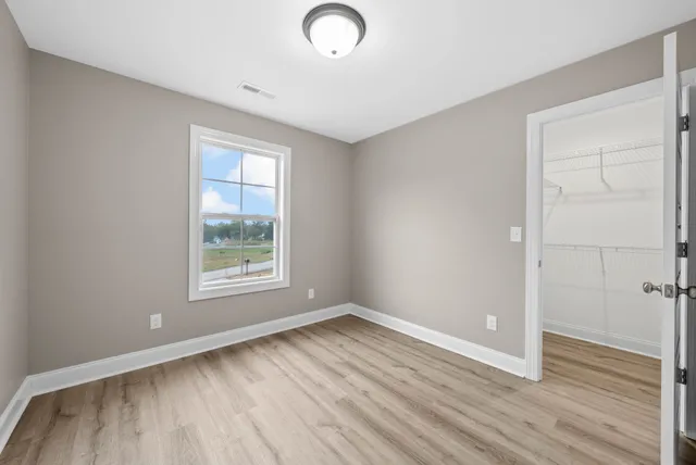 an empty room with wooden floor and windows