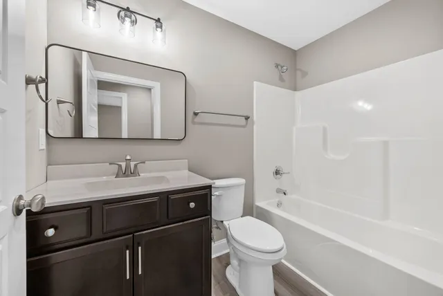 a bathroom with a toilet a sink a tub and mirror