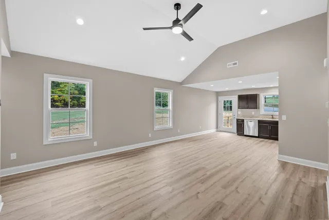 a view of an empty room with a window and wooden floor
