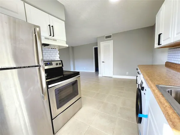 a kitchen with stainless steel appliances granite countertop a refrigerator a stove and a sink