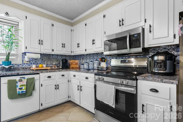 a kitchen with stainless steel appliances granite countertop a stove a sink and a microwave