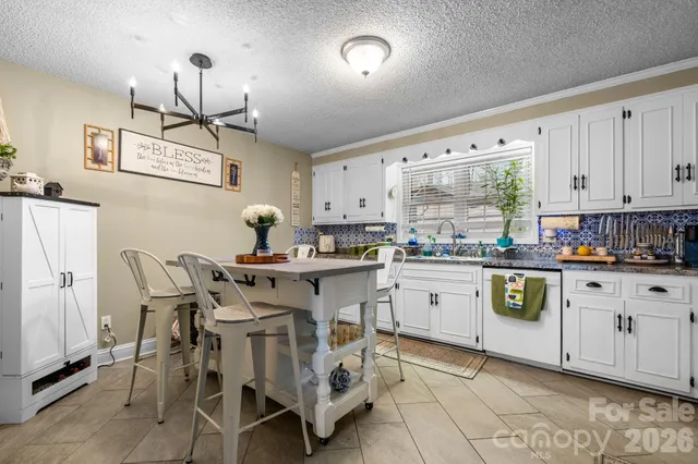 a kitchen with stainless steel appliances a white table chairs and a refrigerator