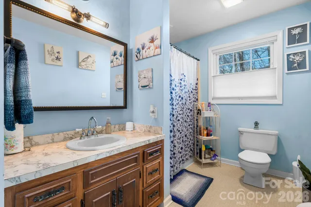 a bathroom with a granite countertop toilet sink and mirror