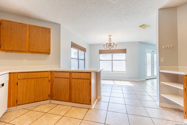 a view of a kitchen with wooden cabinet and two windows