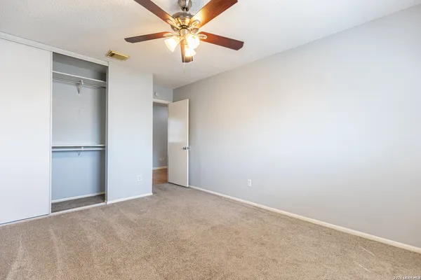 an empty room with a ceiling fan and a bathroom