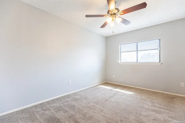an empty room with a window and a fan