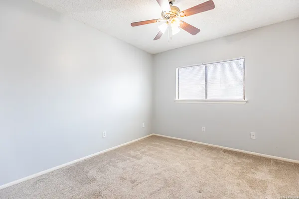 an empty room with a window and a fan