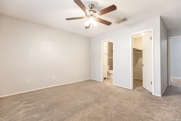 an empty room with closet and a ceiling fan