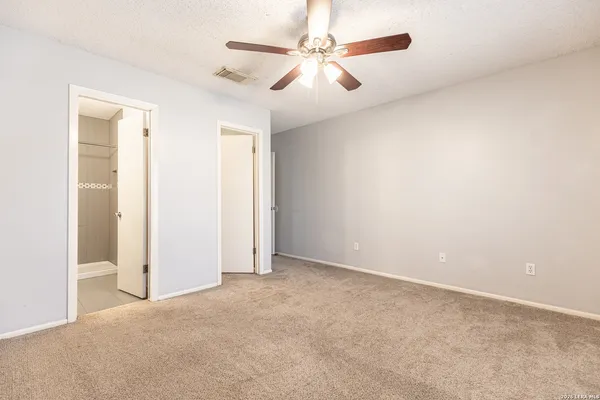 an empty room with windows and fan