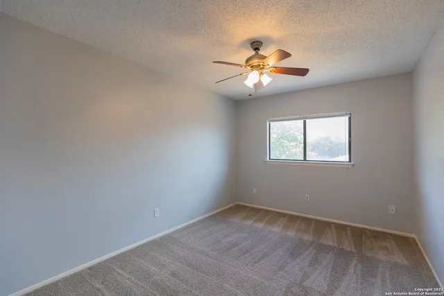 an empty room with a window and ceiling fan