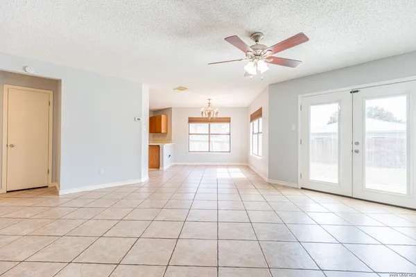 a view of an empty room with window and chandelier fan