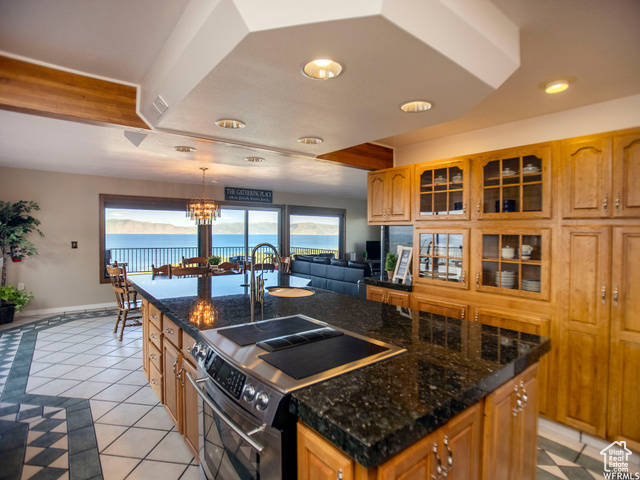 588 Raspberry Patch Road Garden City, UT 84028 - Photo 17 of 74 Kitchen featuring stainless steel range with electric stovetop, decorative light fixtures, light tile patterned floors, an island with sink, and dark stone counters