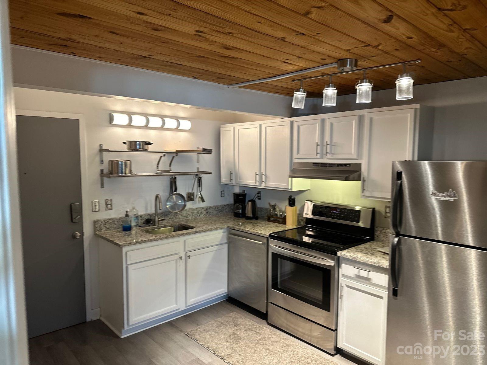 a kitchen with stainless steel appliances a stove a sink and white cabinets