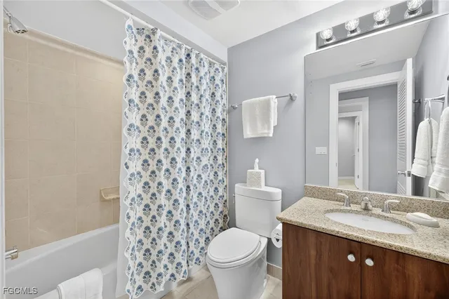 a bathroom with a granite countertop toilet a sink a mirror a shower curtain and a sink