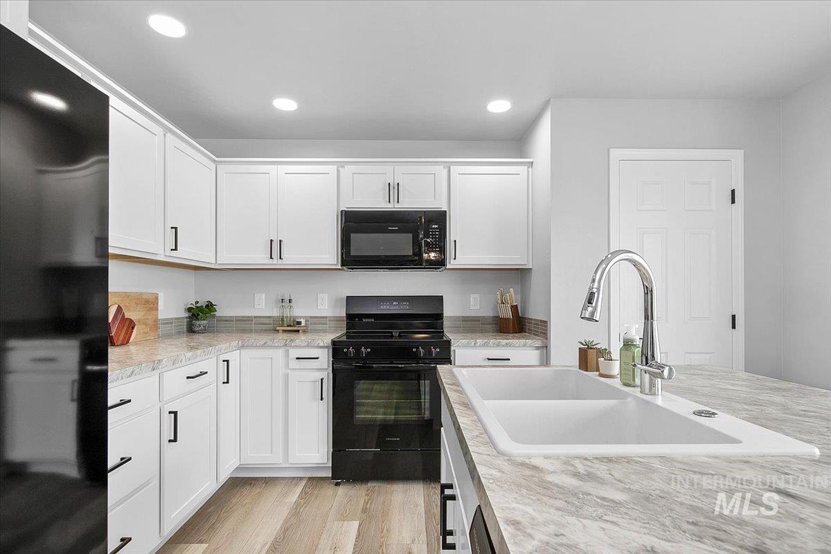 13520 Farwell Street Caldwell, ID 83607 - Photo 12 of 26 Kitchen featuring black appliances, white cabinetry, light wood finished floors, recessed lighting, and light stone counters