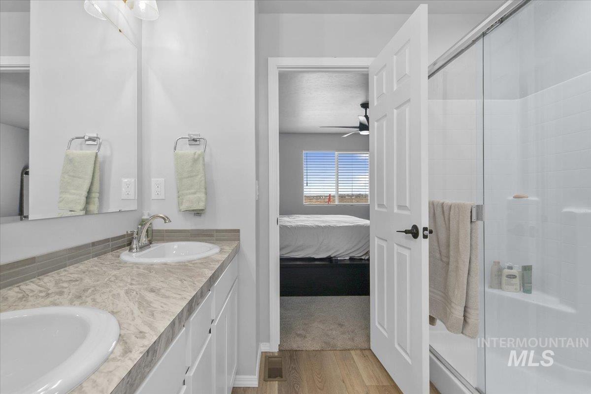 13520 Farwell Street Caldwell, ID 83607 - Photo 22 of 26 Full bathroom with connected bathroom, double vanity, a stall shower, and light wood-style floors