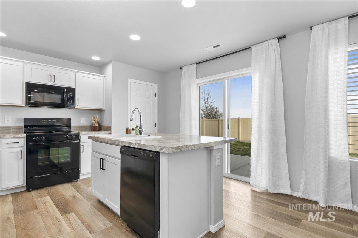 13520 Farwell Street Caldwell, ID 83607 - Photo 10 of 26 Kitchen featuring black appliances, white cabinets, a center island with sink, light wood finished floors, and recessed lighting