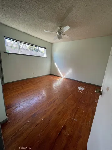an empty room with wooden floor chandelier fan and windows
