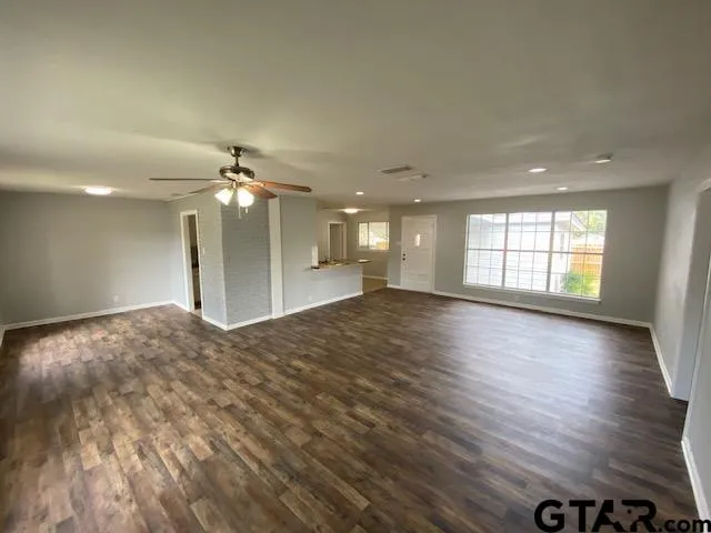 a view of an empty room with window and wooden floor