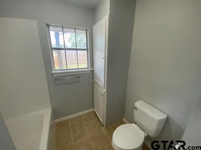 a white toilet sitting next to a bathroom sink and a window