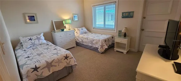 a bedroom with 2 bed and a flat tv screen on dresser