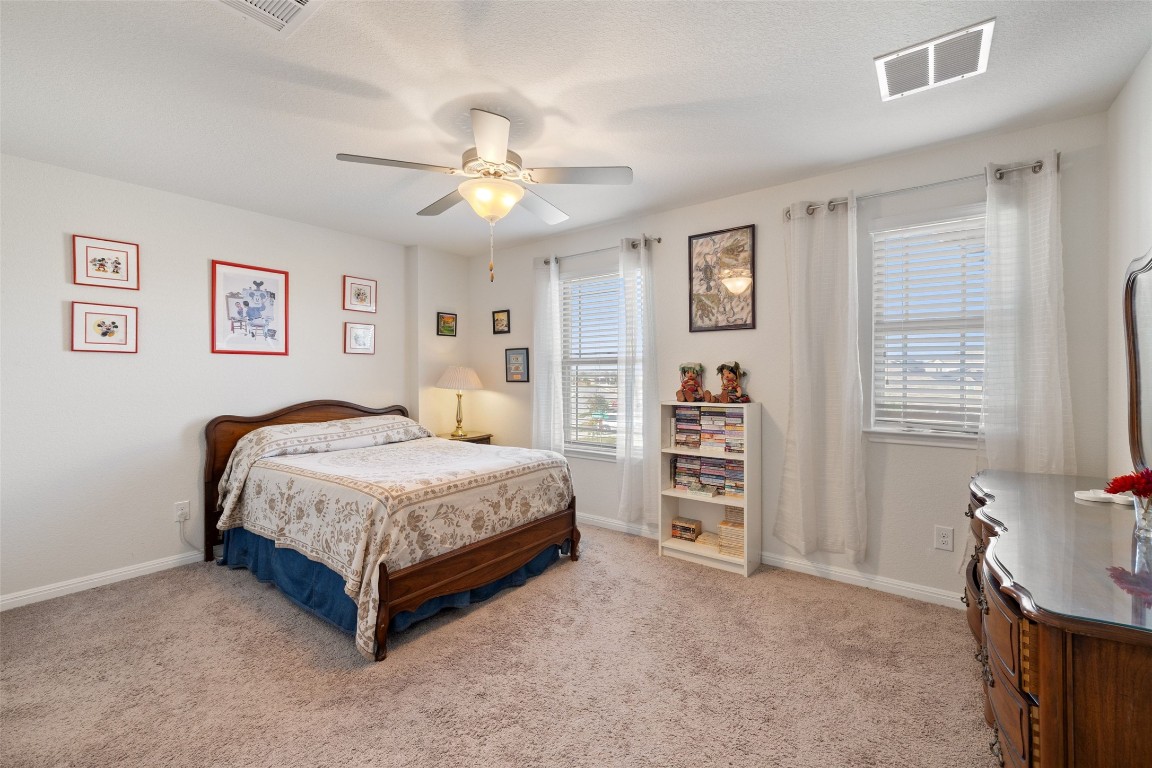 11701 Pecangate Way Manor, TX 78653 - Photo 29 of 40 a spacious bedroom with a bed a book shelf and a window