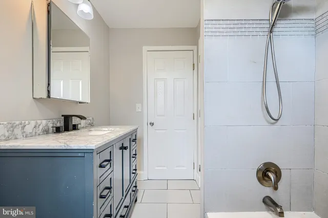 a bathroom with a granite countertop sink a mirror and a shower