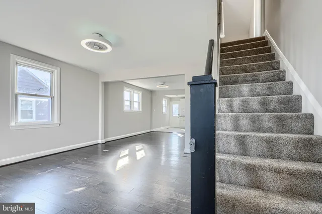 a view of an empty room with wooden floor and windows