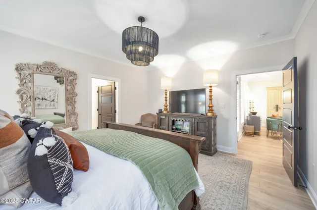 a bedroom with a large bed and a chandelier