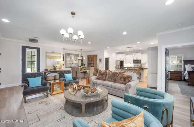 a living room with furniture kitchen view and a chandelier