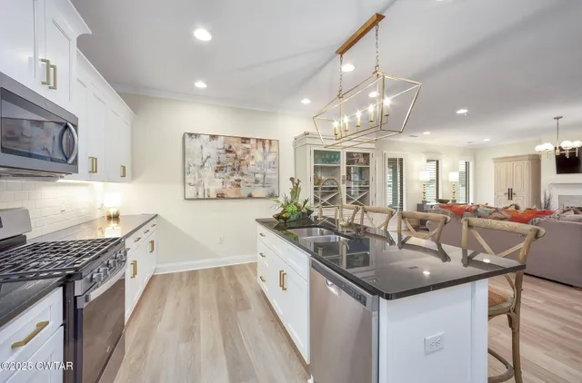 a large kitchen with stainless steel appliances granite countertop a lot of counter space and wooden floors