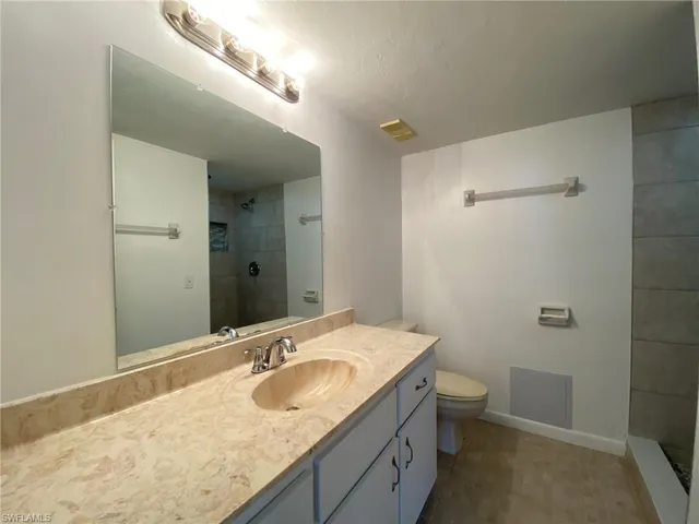 a bathroom with a granite countertop sink a mirror and a toilet