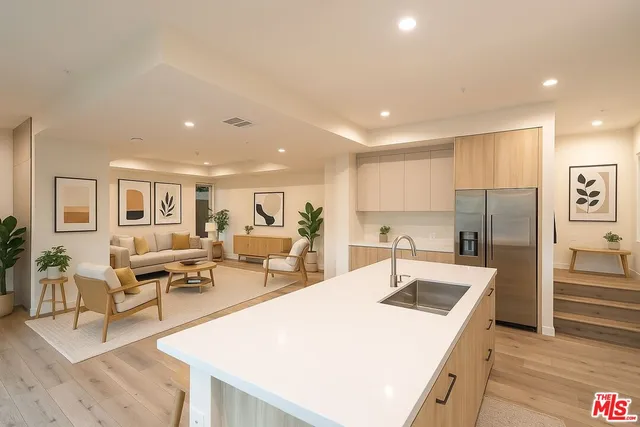 a kitchen with stainless steel appliances granite countertop a sink dishwasher a refrigerator and white cabinets with wooden floor