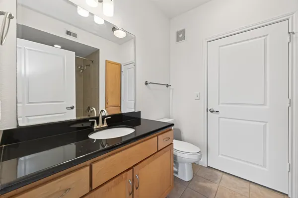 a bathroom with a granite countertop sink a toilet a mirror and shower