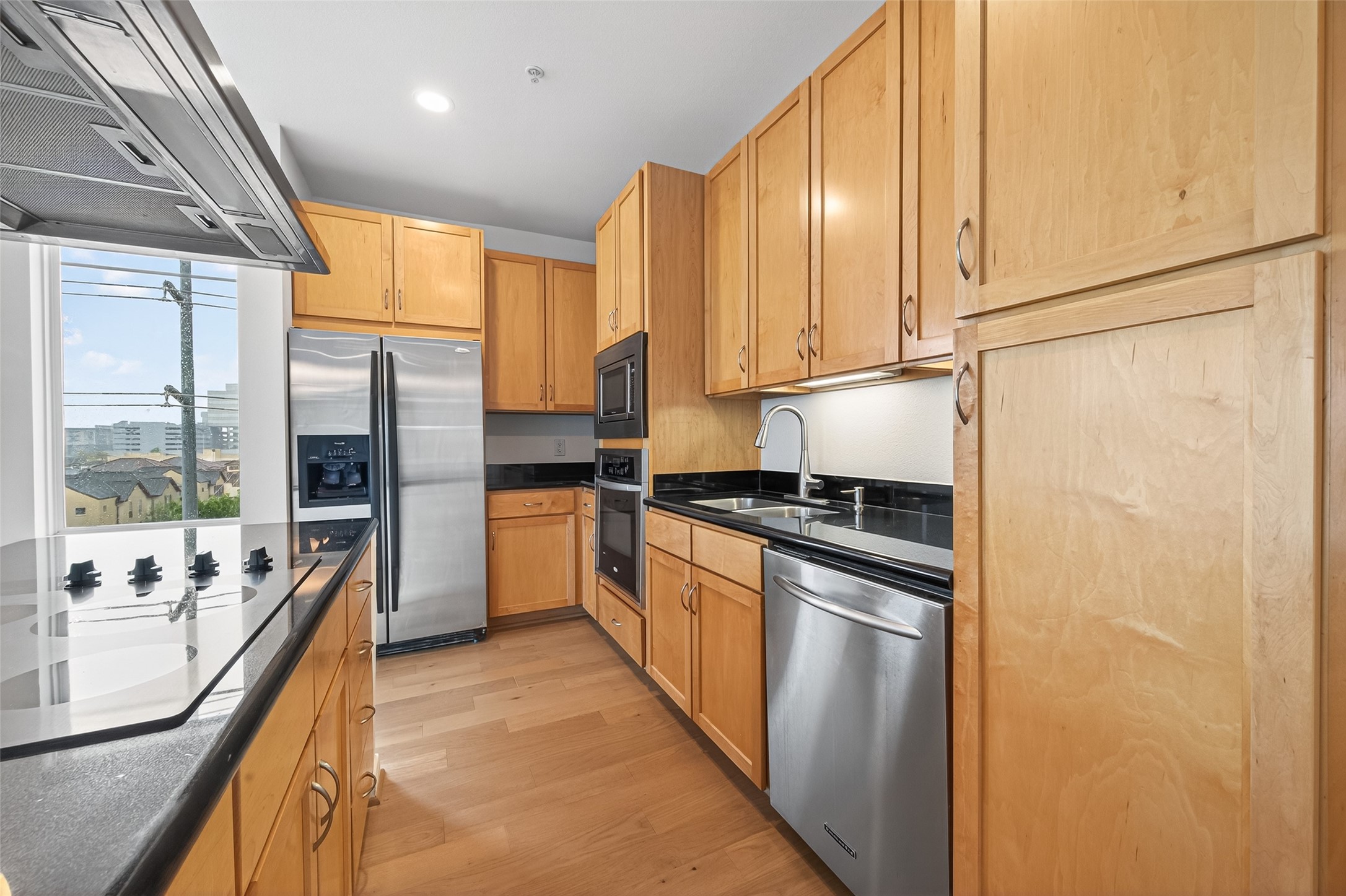 505 Jackson Hill Street, Unit 404 Houston, TX 77007 - Photo 4 of 24 a kitchen with stainless steel appliances granite countertop a refrigerator a sink dishwasher a stove and white countertops with wooden floor