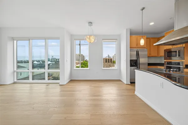 a view of an empty room with kitchen and window