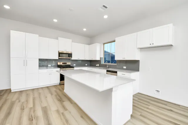 a large kitchen with kitchen island a sink a stove and white cabinets