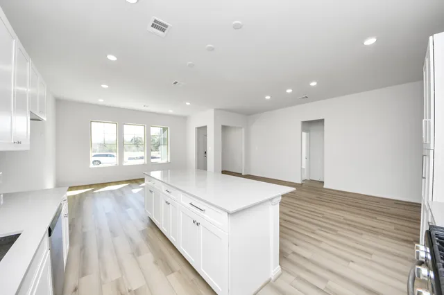 a large white kitchen with wooden floors and wide window