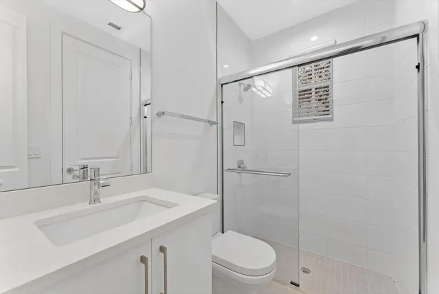 a bathroom with a shower sink vanity mirror and toilet