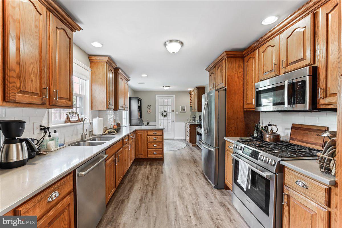 400 Southcroft Road Springfield, PA 19064 - Photo 11 of 44 a kitchen with stainless steel appliances a stove top oven a sink dishwasher a refrigerator and cabinets with wooden floor