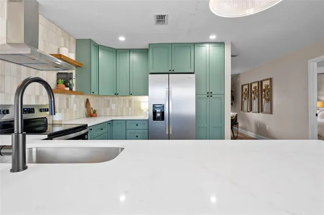 a kitchen with stainless steel appliances kitchen island granite countertop a refrigerator a stove and a sink with wooden floor