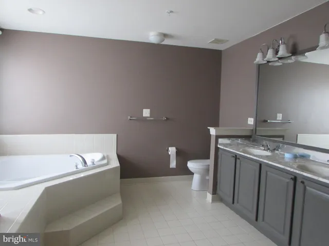 a bathroom with a granite countertop sink a toilet and a mirror