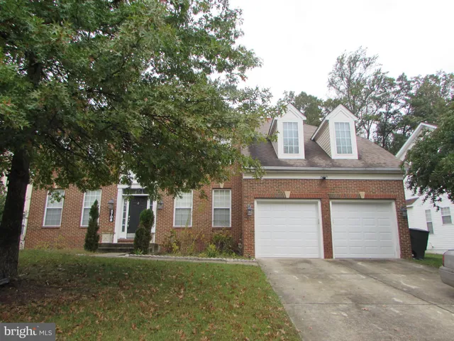 a front view of a house with a garden and trees
