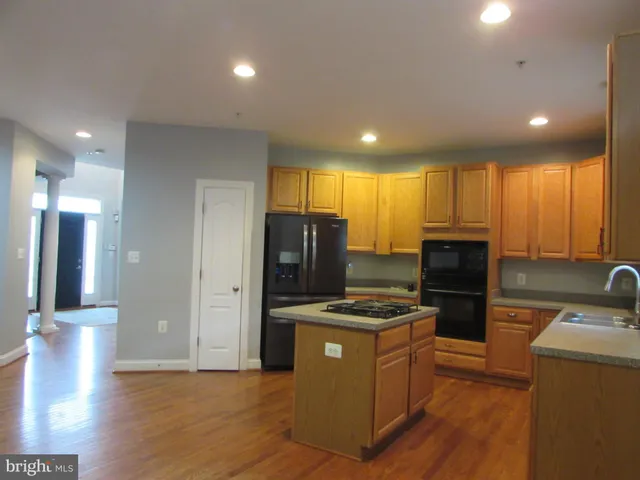 a view of a kitchen with a sink refrigerator and wooden floor