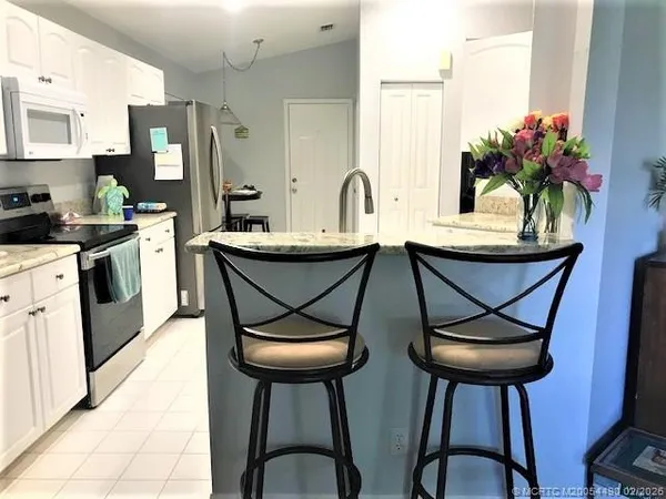 a kitchen with stainless steel appliances a table and chairs in it