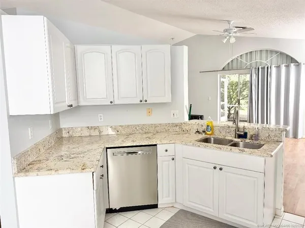 a kitchen with white cabinets white appliances sink and window